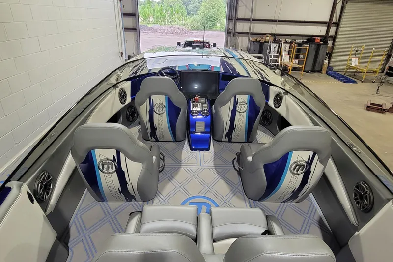 Slide: The Image of 2022 Mystic Powerboats C4000 interior with sleek seating and modern dashboard in a garage setting. - 17
