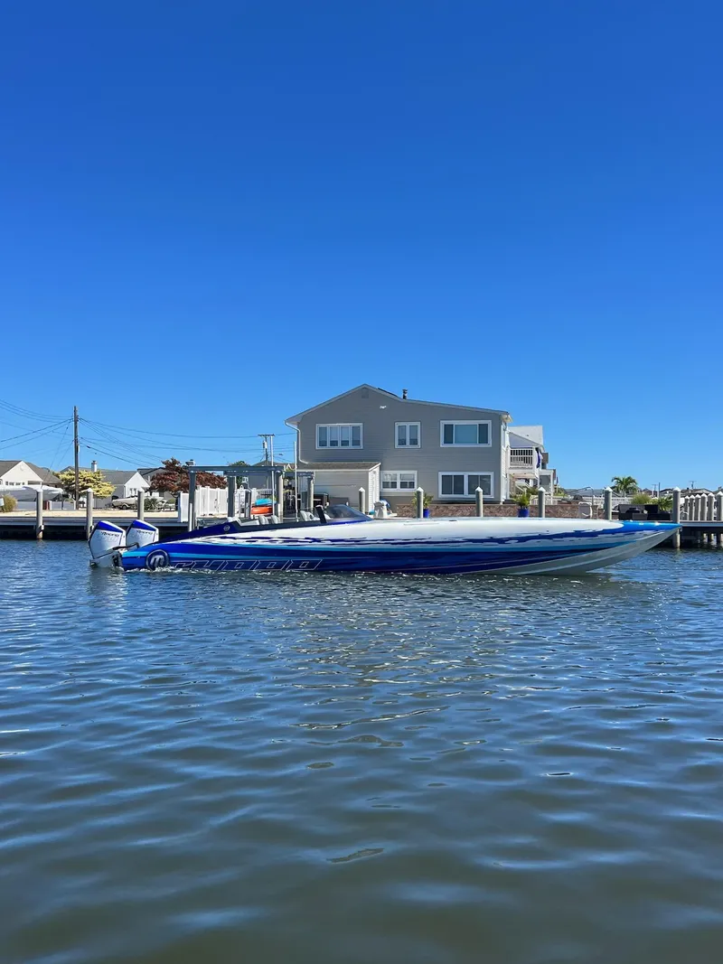 Slide: The Image of 2022 Mystic Powerboats C4000 on water near waterfront house under clear blue sky. - 2
