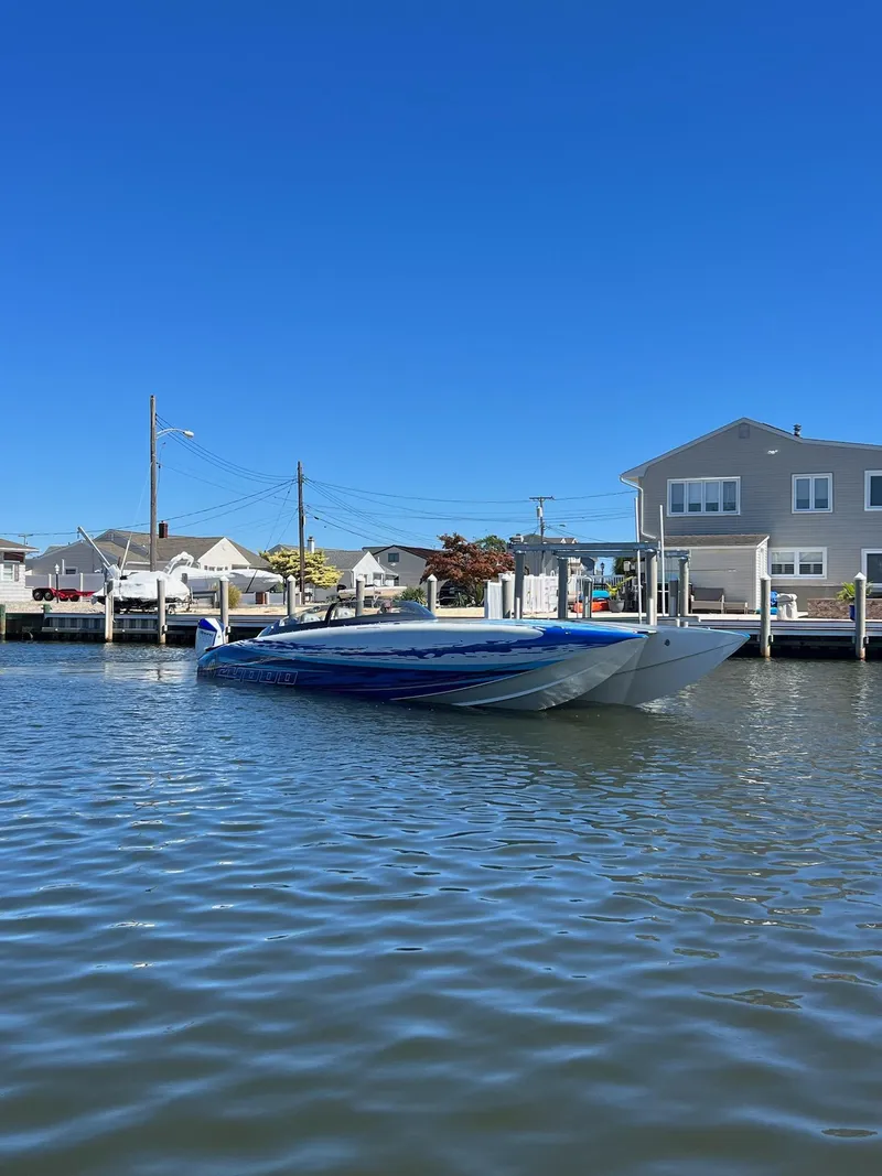 Slide: The Image of 2022 Mystic Powerboats C4000 on calm water near residential docks under clear blue sky. - 4