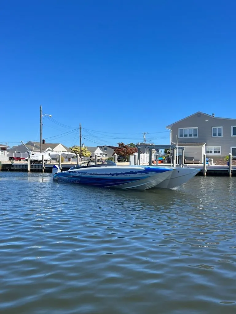 Slide: The Image of 2022 Mystic Powerboats C4000 on calm water near residential docks under clear blue sky. - 5