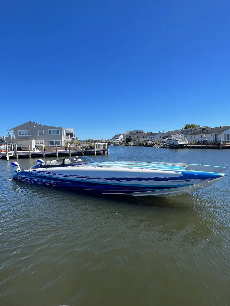 Slide: The Image of 2022 Mystic Powerboats C4000 on water, sleek design, vibrant blue color, residential backdrop. - 6