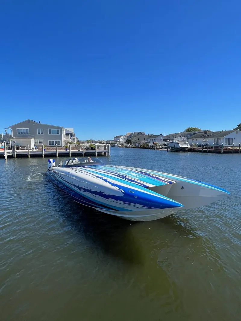 Slide: The Image of 2022 Mystic Powerboats C4000 in a serene waterfront setting under a clear blue sky. - 7