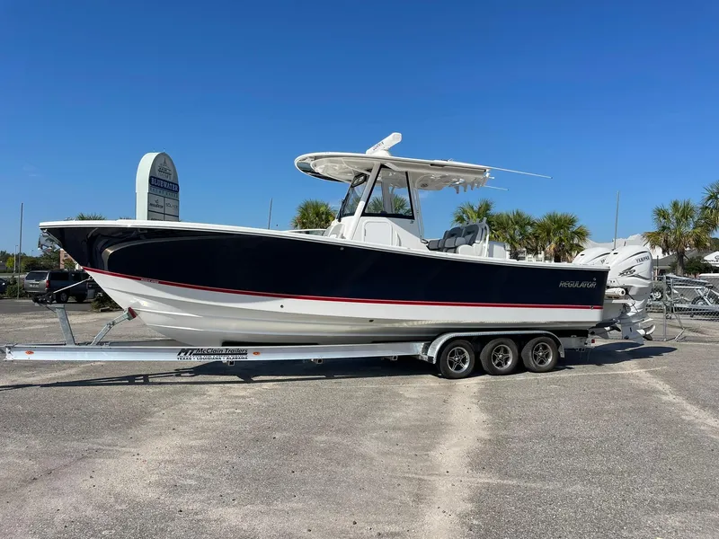 Slide: The Image of 2022 Regulator 31 boat on trailer, parked outdoors under clear blue sky. - 1