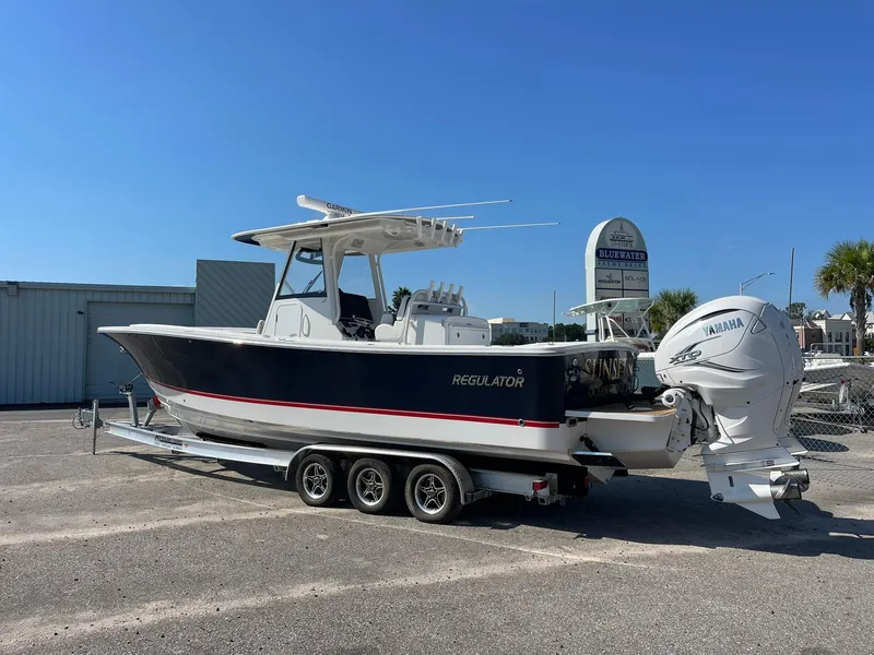 Slide: The Image of 2022 Regulator 31 boat with Yamaha engines on a trailer in a parking lot. - 2
