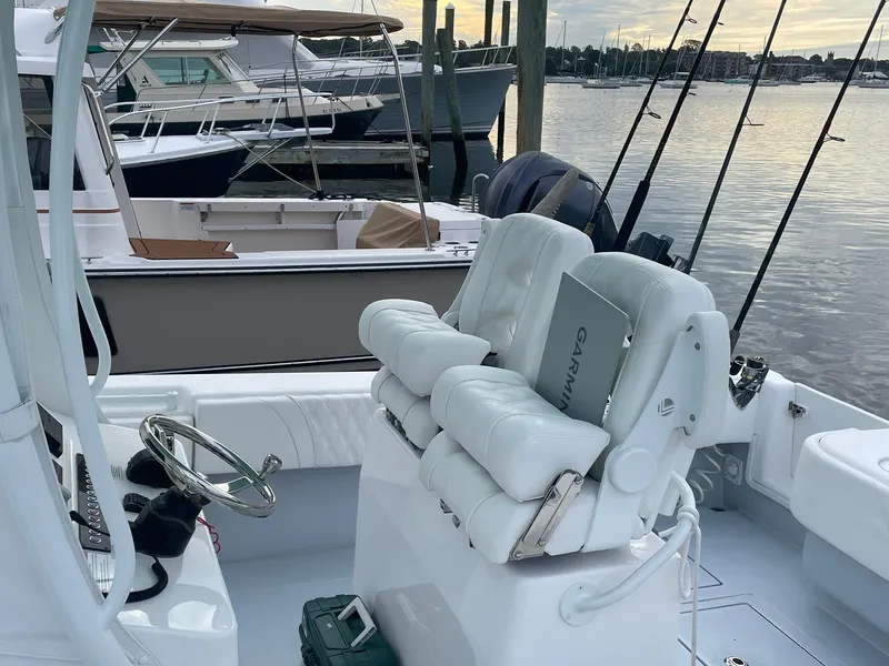 Slide: The Image of 2024 Contender 28 Tournament boat interior with white seating and fishing rods at a marina. - 7