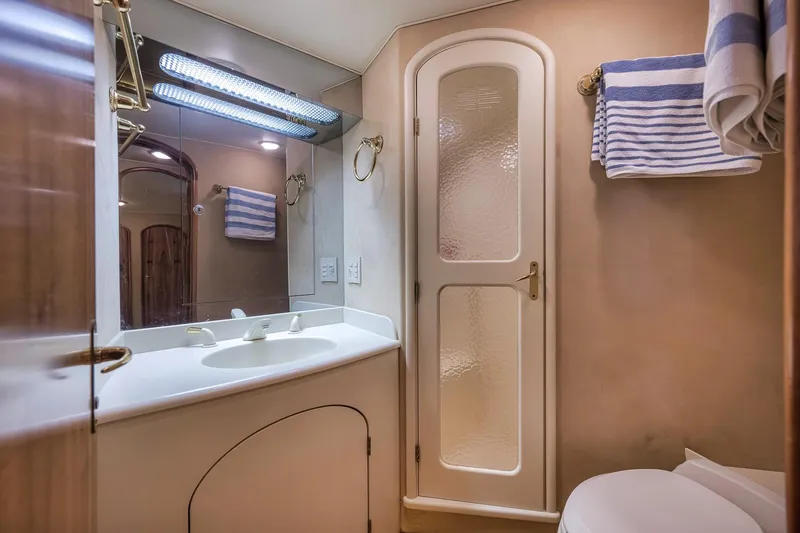Slide: The Image of Bathroom interior of 1999 Hines-Farley SPORTFISHERMAN yacht with sink, mirror, and striped towels. - 52