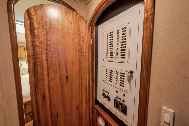 Slide: The Image of Electrical panel inside 1999 Hines-Farley SPORTFISHERMAN yacht, featuring wooden door and control switches. - 58