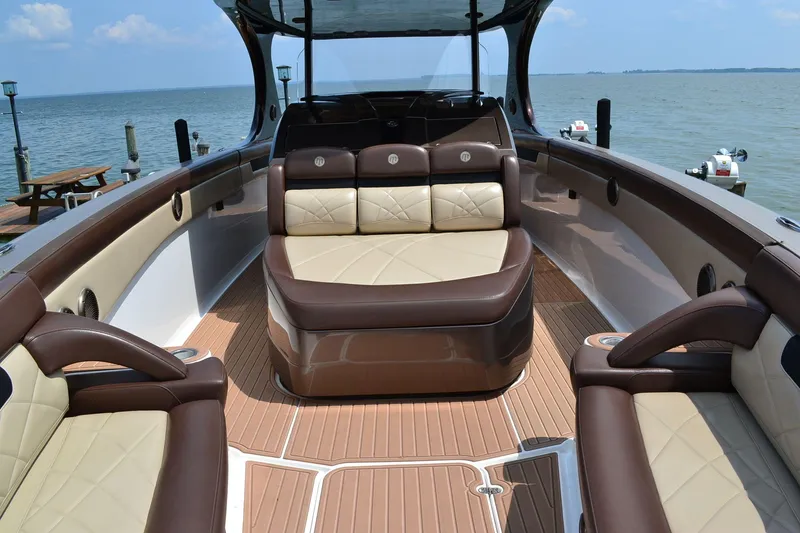 Slide: The Image of 2016 Mystic Powerboats M4200 interior with luxurious seating and wood finish, docked by the sea. - 13