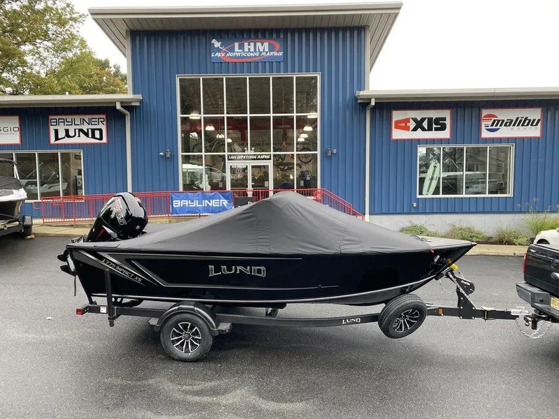 Slide: The Image of 2025 Lund 1775 Impact XS Sport boat covered on trailer outside dealership. - 17