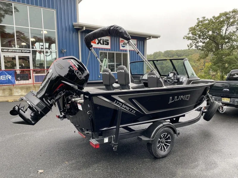 Slide: The Image of 2025 Lund 1775 Impact XS Sport boat on trailer, parked outside dealership. - 3