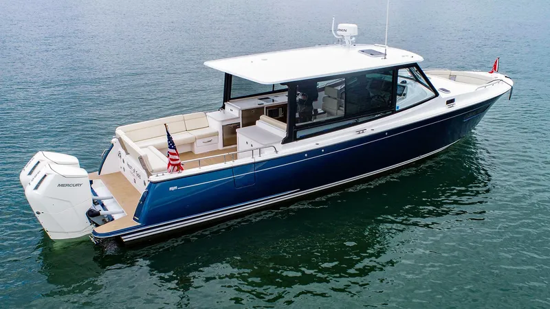 Slide: The Image of 2024 MJM 4 boat on water, sleek design, blue hull, outboard motor. - 2