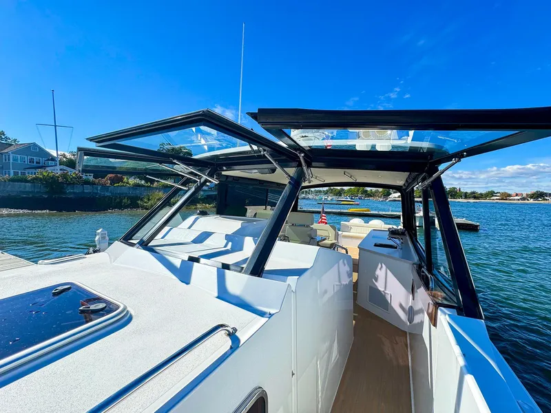 Slide: The Image of 2024 MJM 4 boat with open roof, docked by scenic waterfront. - 5
