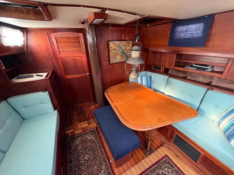 Slide: The Image of 1981 Endeavour 40 yacht interior with wooden dining area and blue cushioned seating. - 15