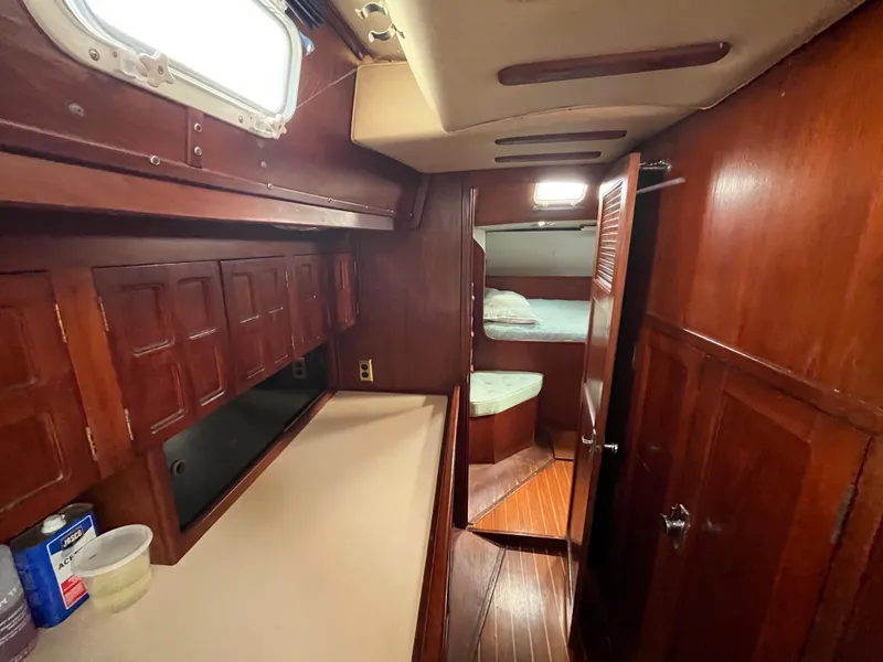 Slide: The Image of 1981 Endeavour 40 yacht interior with wooden cabinetry and cozy sleeping area. - 19