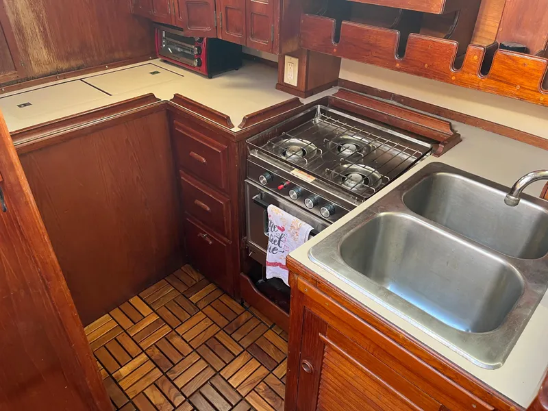 Slide: The Image of 1981 Endeavour 40 yacht kitchen with wooden cabinetry, dual sink, and gas stove. - 38