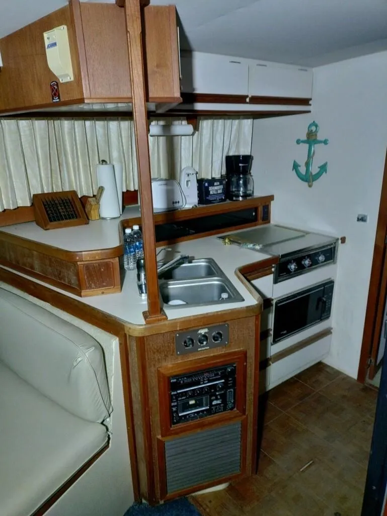 Slide: The Image of 1988 Carver Mariner 32 yacht kitchen with sink, stove, and wooden cabinetry. - 24