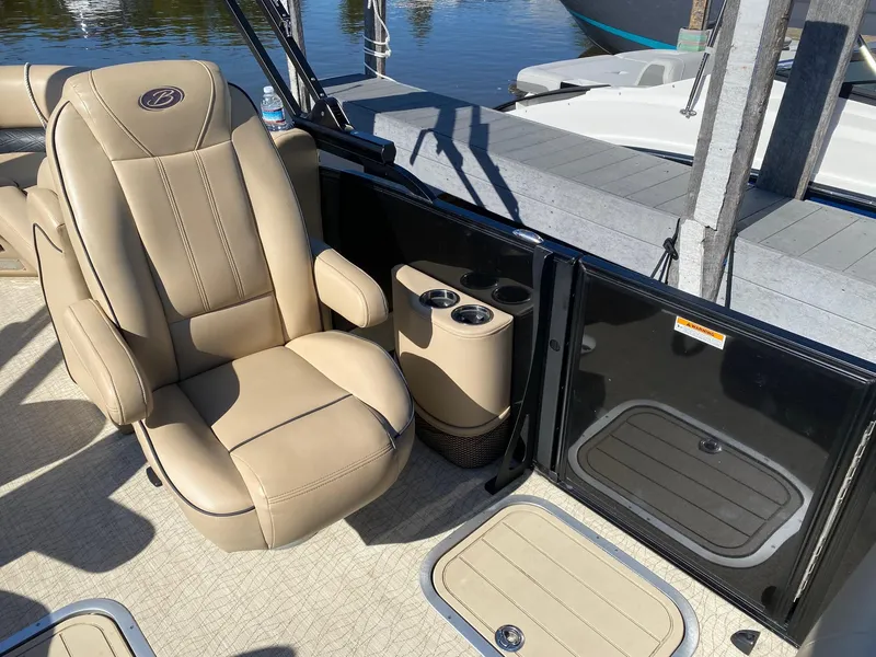 Slide: The Image of 2019 Barletta E22QC boat interior with beige seating and cup holders by the dock. - 10