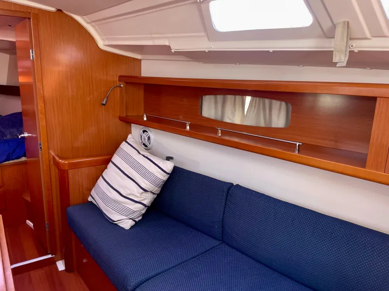 Slide: The Image of Interior of 2010 Beneteau Oceanis 37 sailboat with blue sofa and wooden accents. - 12