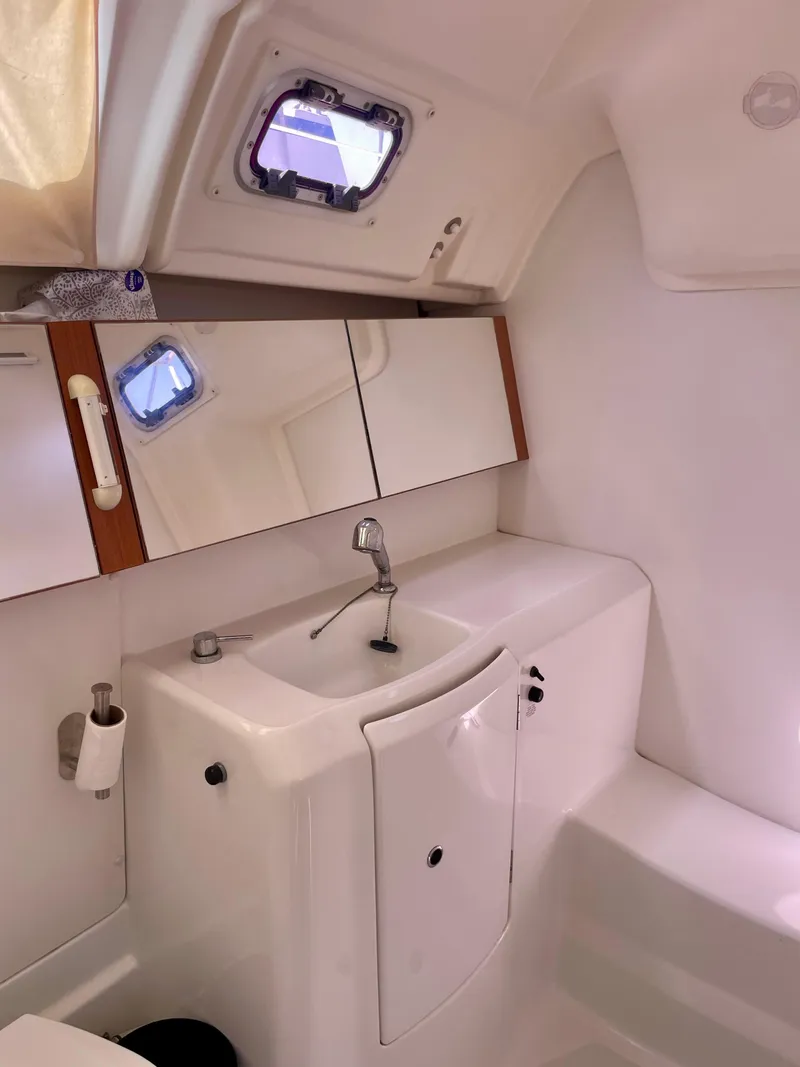 Slide: The Image of 2010 Beneteau Oceanis 37 yacht bathroom with sink, mirror, and porthole window. - 23