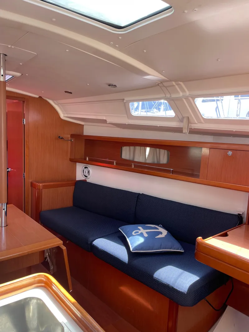 Slide: The Image of Interior of 2010 Beneteau Oceanis 37 sailboat with blue sofa and anchor-themed pillow. - 34