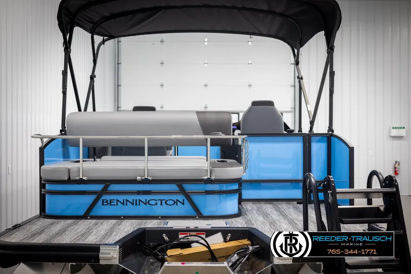 Slide: The Image of 2025 Bennington 23 SSBSE pontoon boat with blue exterior and black canopy in showroom. - 7