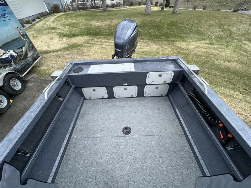 Slide: The Image of 2023 Duckworth 20 NAV SPT boat interior with storage compartments and motor, parked on grass. - 7