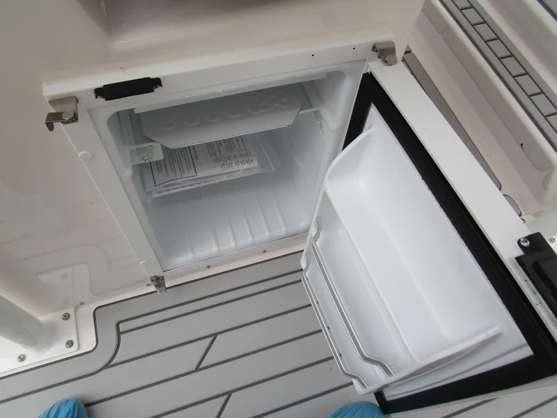Slide: The Image of Open mini fridge on Solara S-250 CW boat, 2025 model, with gray deck flooring. - 28