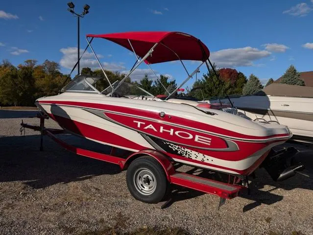 Slide: The Image of 2010 Tahoe Q5i boat with red canopy on trailer, parked outdoors. - 22