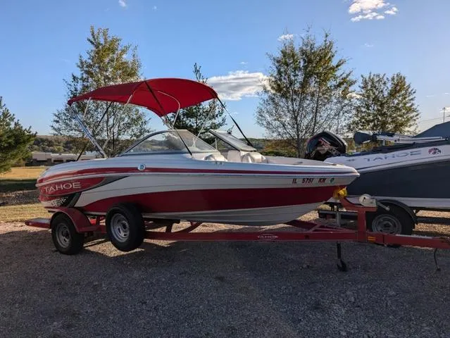 Slide: The Image of 2010 Tahoe Q5i boat with red canopy on trailer, parked outdoors. - 24