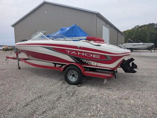 Slide: The Image of 2010 Tahoe Q5i boat on trailer, red and white design, parked near a large building. - 4