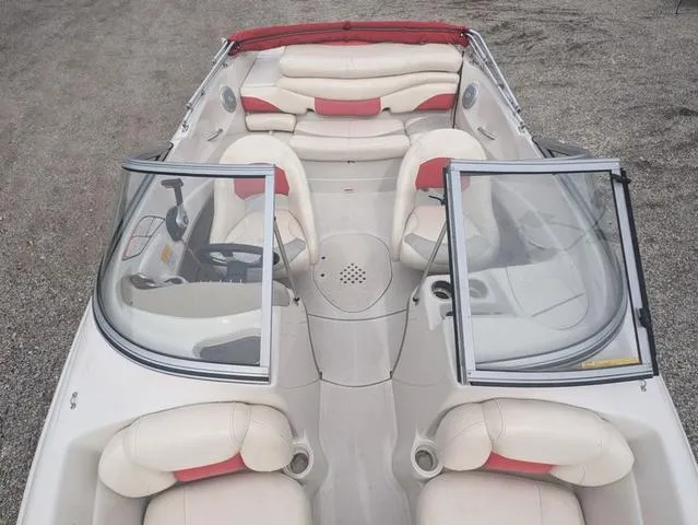 Slide: The Image of 2010 Tahoe Q5i boat interior with beige and red seating, open windshield, and steering console. - 7