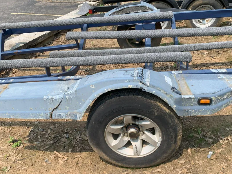 Slide: The Image of 2003 MasterCraft ProStar 197 boat trailer with worn blue paint and padded supports. - 30