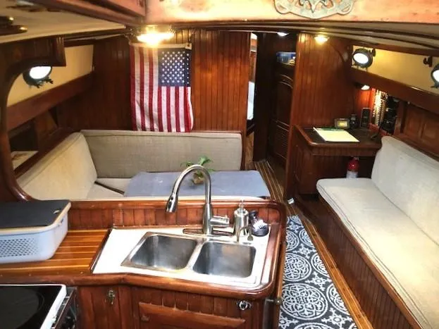 Slide: The Image of 1979 Hans Christian 38 MKII yacht interior with wooden finish, American flag, and cozy seating area. - 10