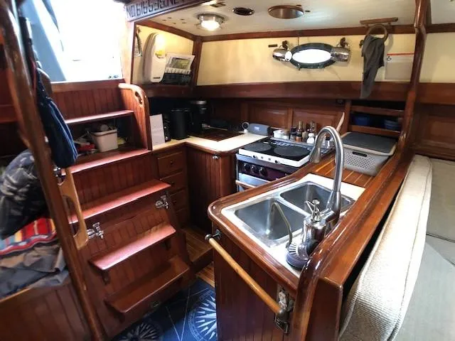 Slide: The Image of 1979 Hans Christian 38 MKII yacht interior with wooden cabinetry and compact kitchen area. - 12