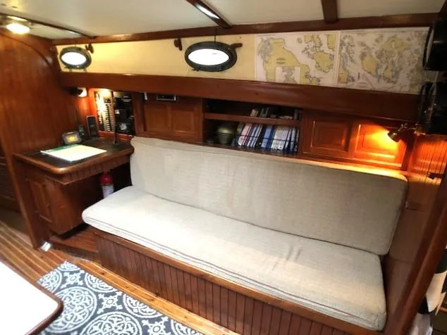 Slide: The Image of Cozy 1979 Hans Christian 38 MKII yacht interior with sofa, navigation desk, and nautical decor. - 14
