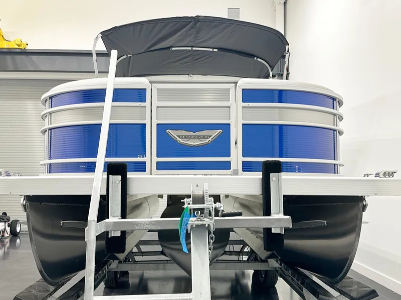 Slide: The Image of 2025 Bennington 23LFBCSR pontoon boat in showroom, featuring blue and silver design. - 4