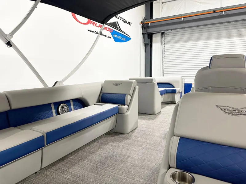 Slide: The Image of 2025 Bennington 23LFBCSR pontoon boat interior with blue and gray seating in a showroom. - 8