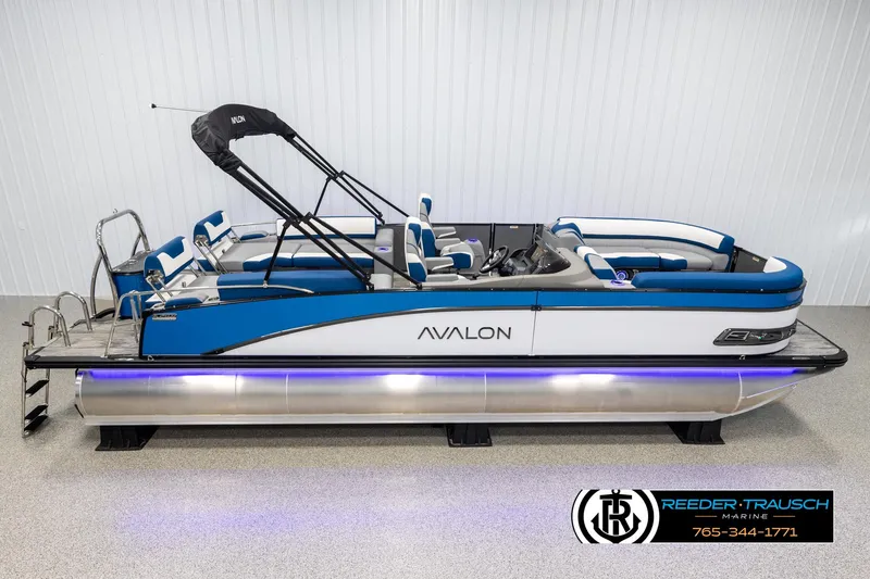 Slide: The Image of 2025 Avalon Catalina QLS pontoon boat with blue accents in showroom. - 1