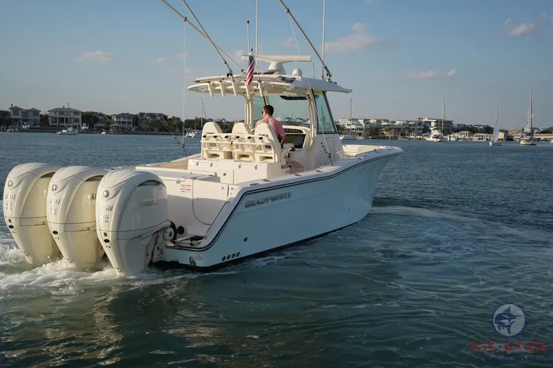 Slide: The Image of 2024 Grady-White Canyon 336 boat cruising on calm waters, featuring triple outboard engines. - 18