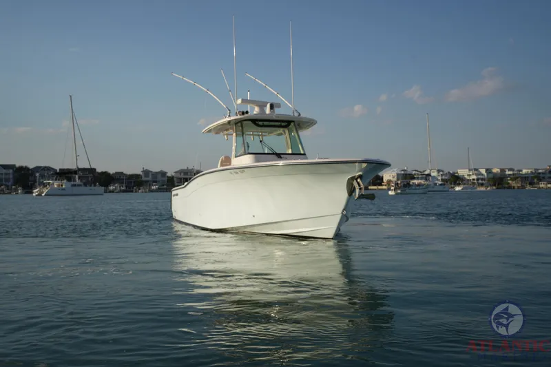 Slide: The Image of 2024 Grady-White Canyon 336 boat on calm water, with a scenic harbor backdrop. - 2