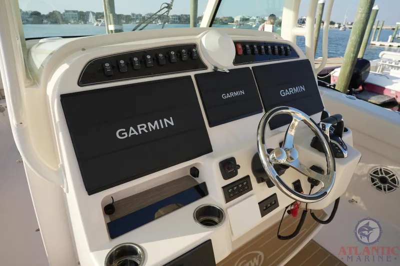 Slide: The Image of 2024 Grady-White Canyon 336 helm with Garmin displays and steering wheel, docked at marina. - 30