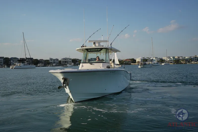 Slide: The Image of 2024 Grady-White Canyon 336 boat cruising on calm waters with cityscape background. - 5