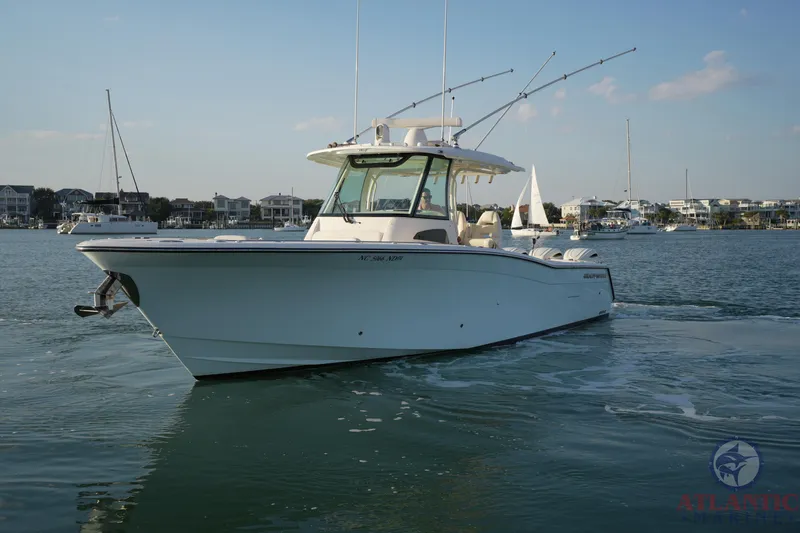 Slide: The Image of 2024 Grady-White Canyon 336 boat on calm water, with coastal buildings in the background. - 6