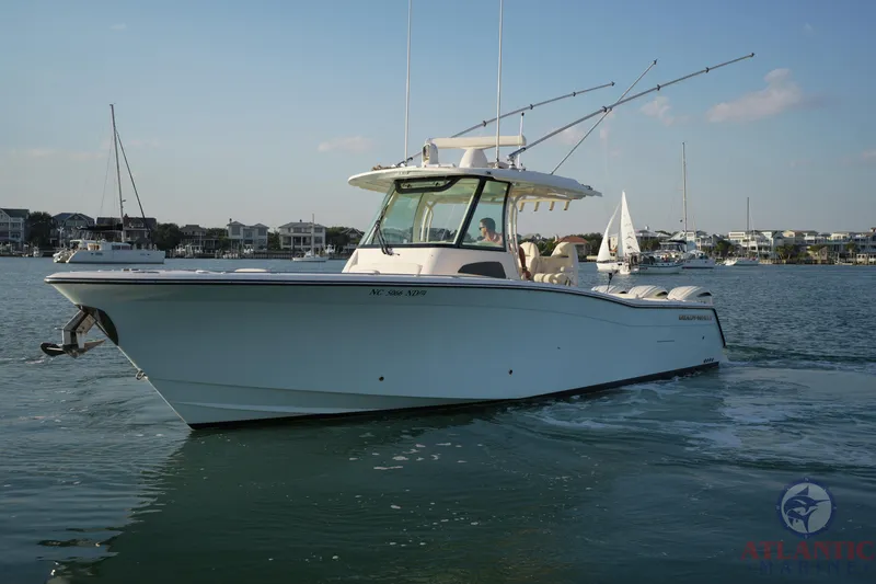 Slide: The Image of 2024 Grady-White Canyon 336 boat cruising on calm waters near a coastal town. - 7