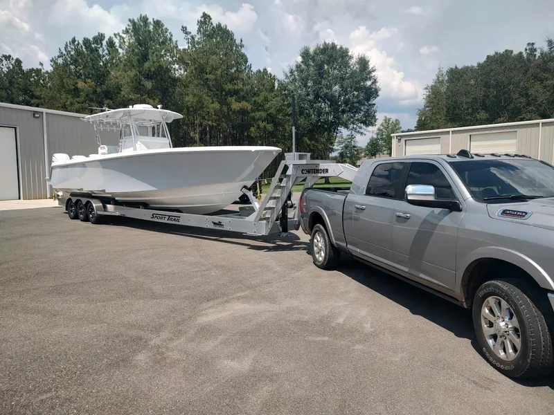 Slide: The Image of 2024 Contender 39 ST boat on trailer, towed by a silver truck, outdoors. - 11