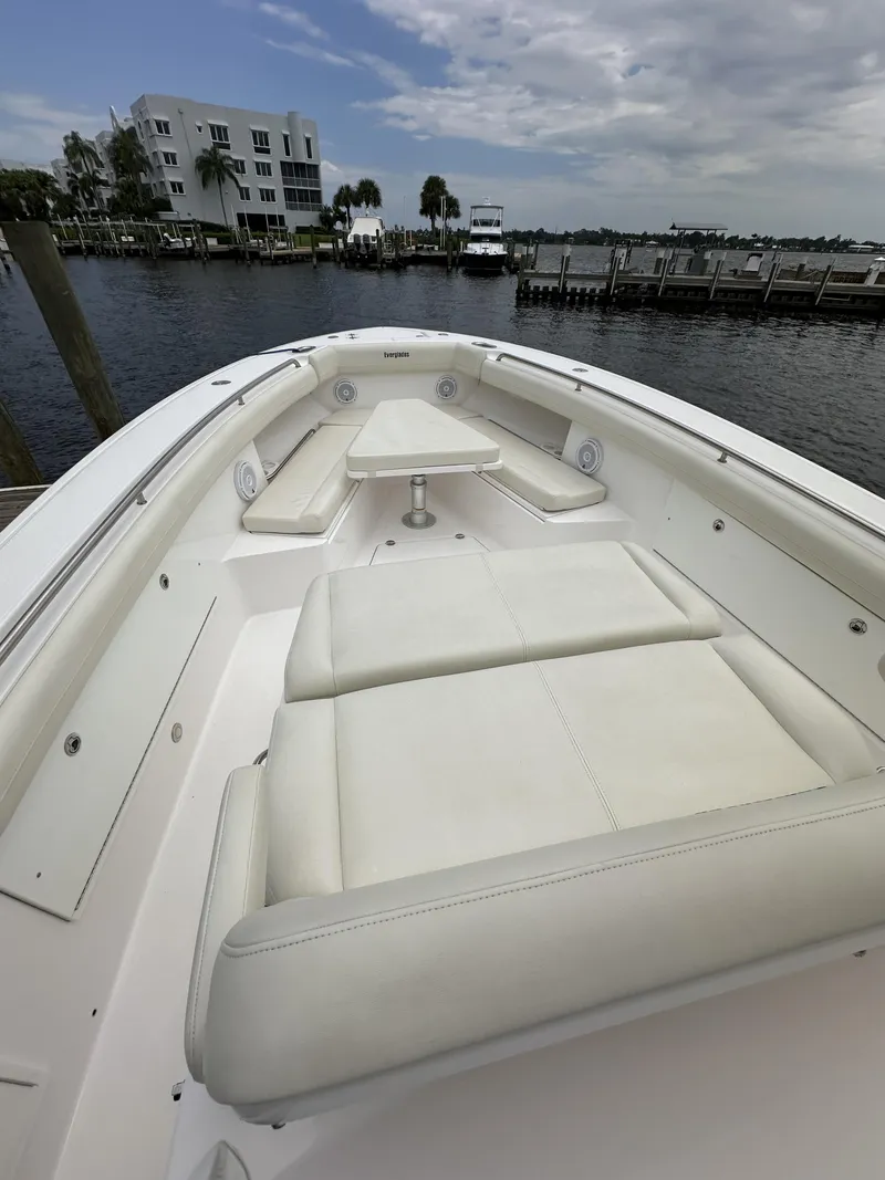 Slide: The Image of 2017 Everglades 435 Center Console boat with white seating, docked by a waterfront. - 21