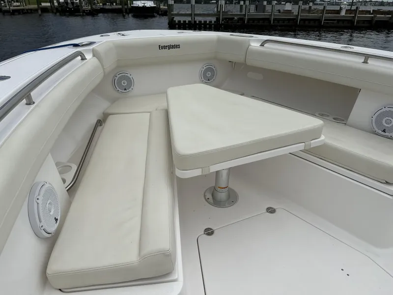 Slide: The Image of 2017 Everglades 435 Center Console boat with cushioned seating and table, docked at marina. - 23
