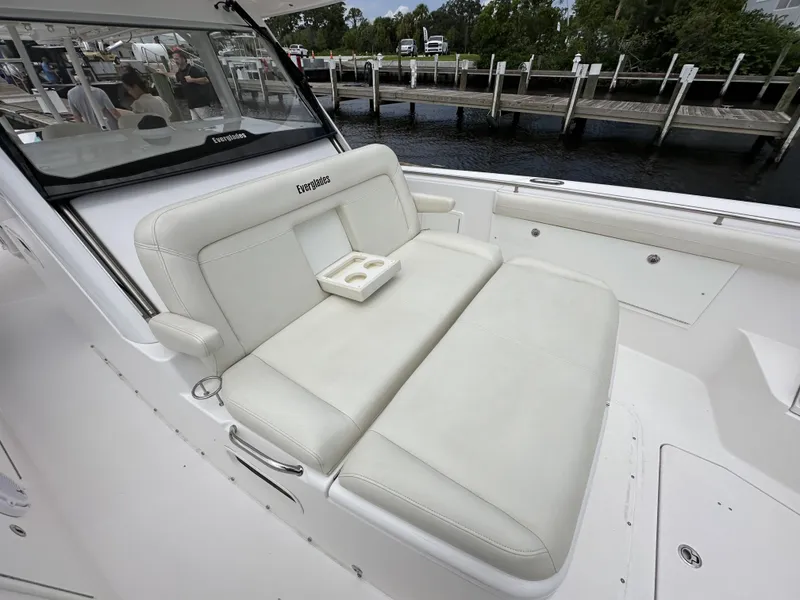 Slide: The Image of 2017 Everglades 435 Center Console boat with white seating and cup holders, docked by the water. - 31
