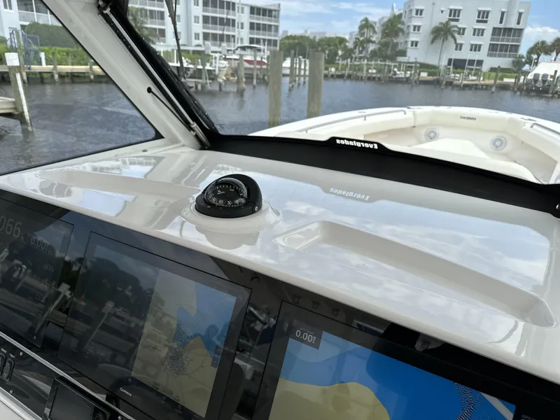 Slide: The Image of 2017 Everglades 435 Center Console boat dashboard with navigation screens, docked near waterfront buildings. - 45