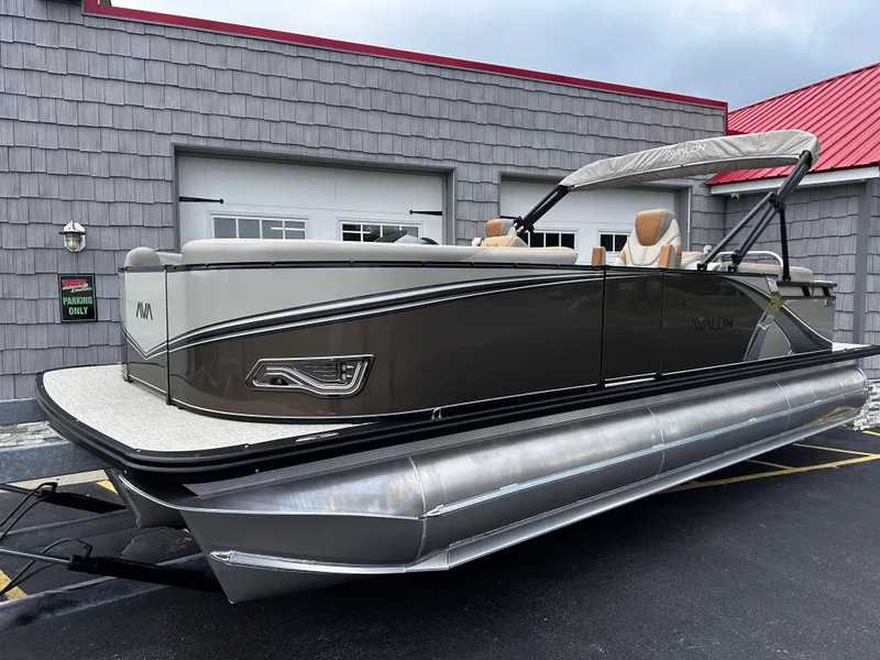 Slide: The Image of 2025 Avalon 2385 LSZ Quad Lounger Tri Toon boat, high performance, parked outdoors. - 0